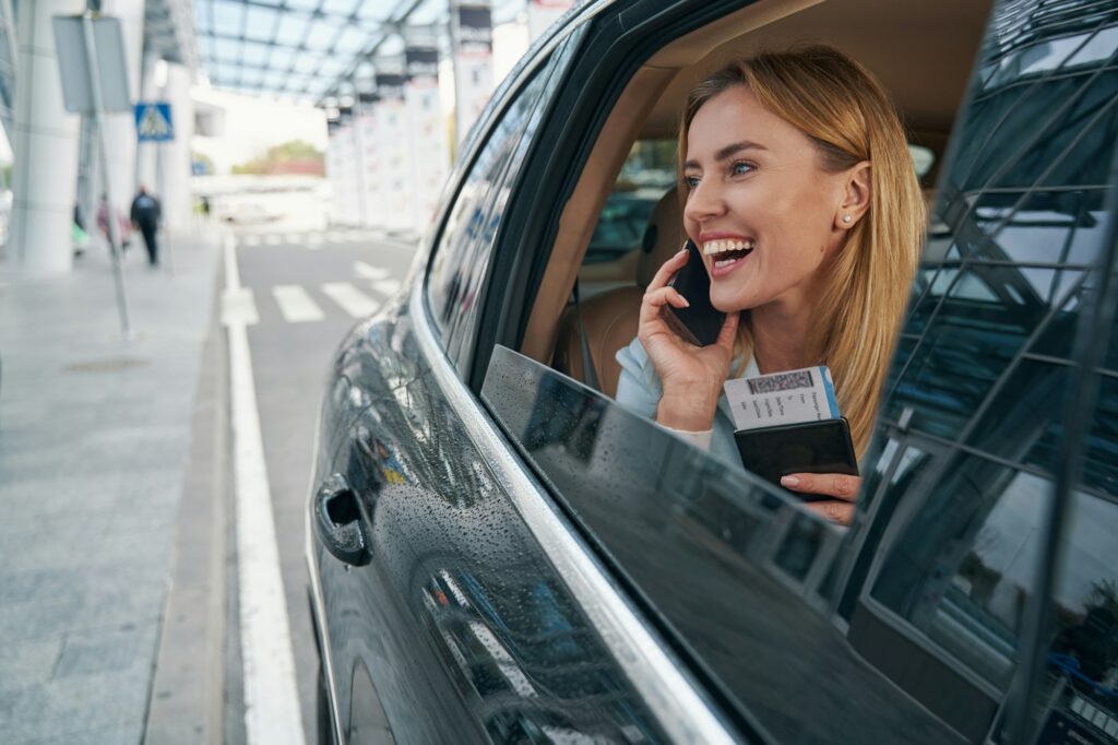 cheerful passenger seated in car talking on smartphone Flughafentaxi Wien